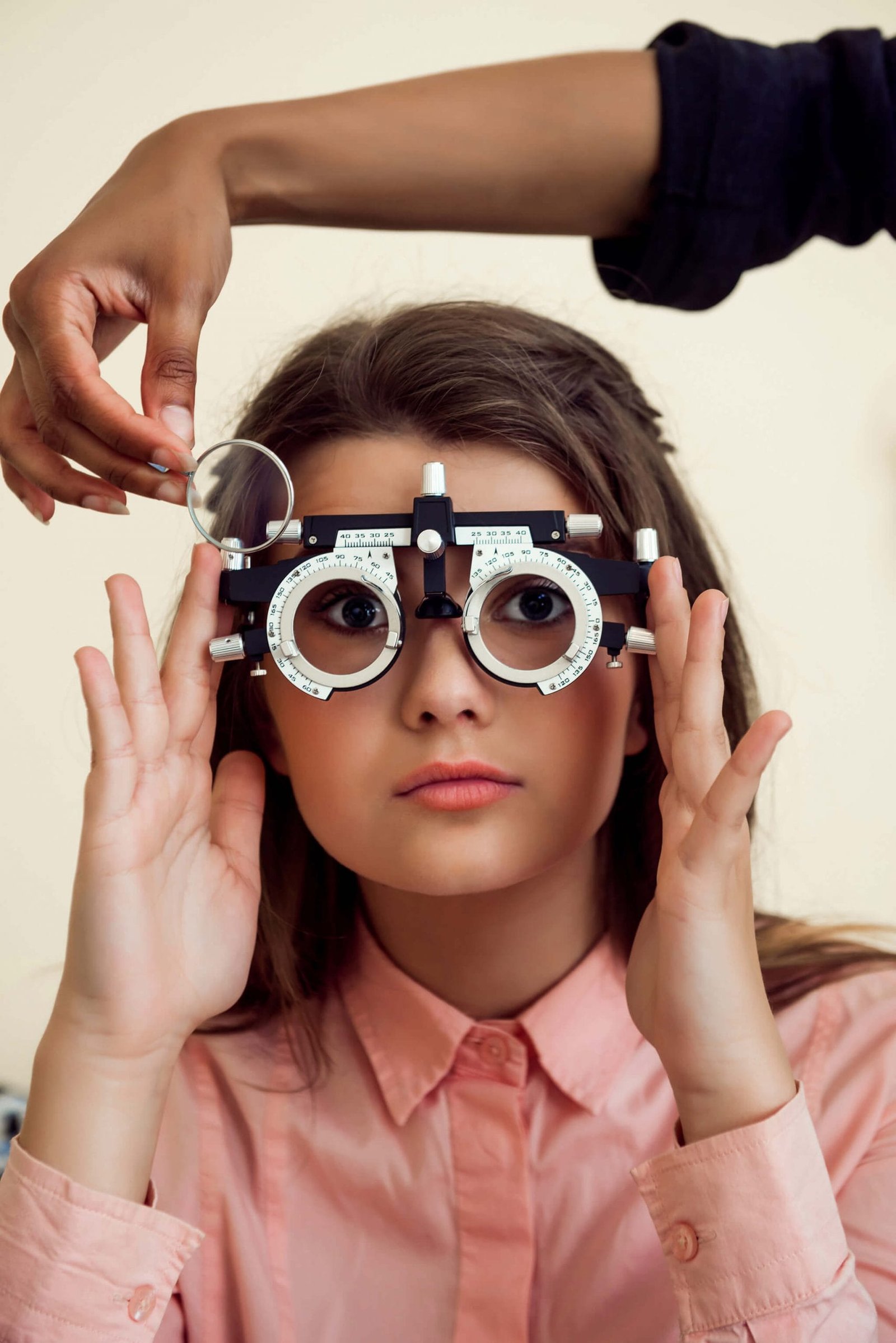 horizontal-shot-interested-curious-caucasian-girl-appointment-with-eye-care-specialist-wearing-phoropter-while-ophthalmologist-checking-her-vision-sitting-yellow-wall